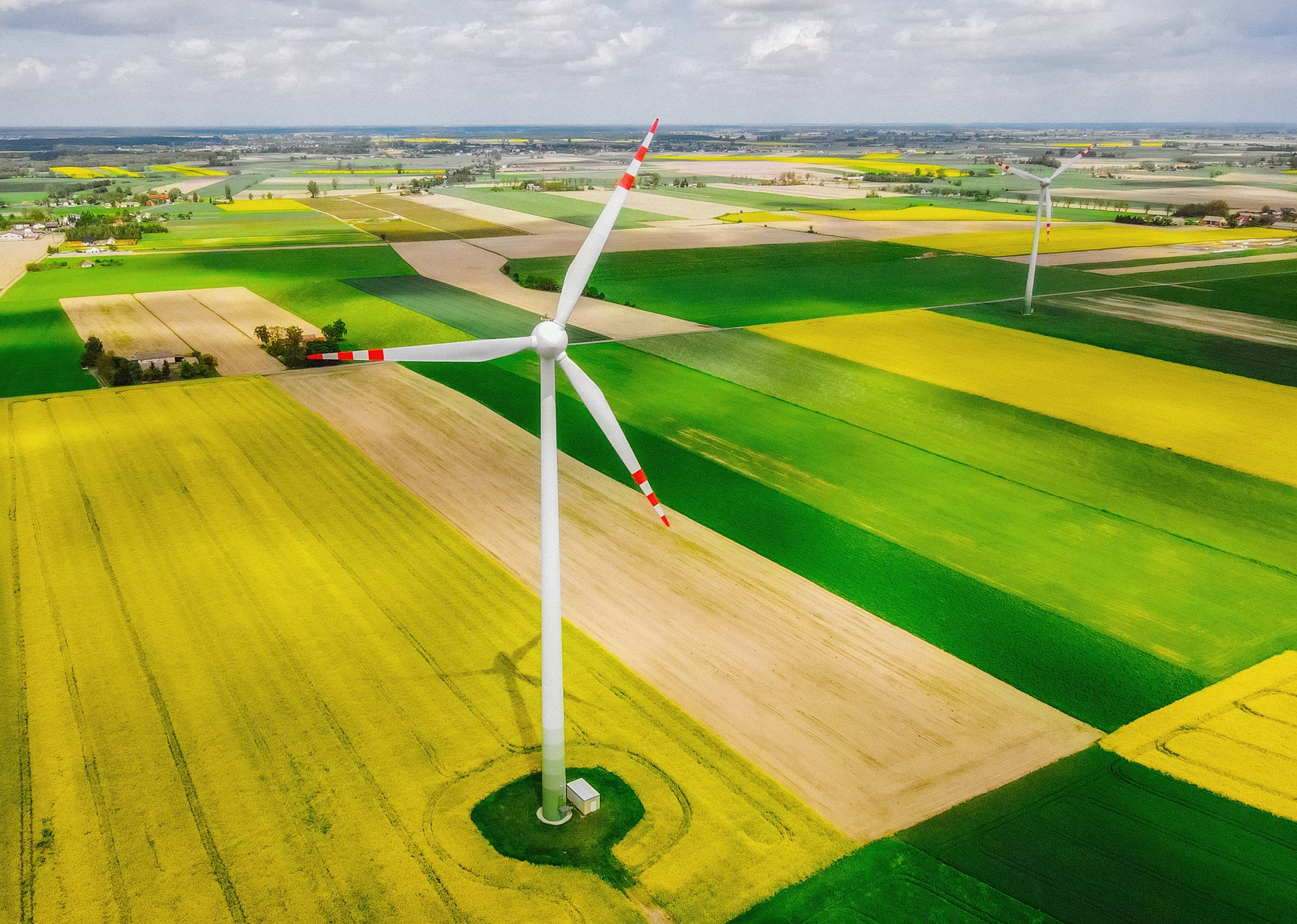 Aerial photo of a wind turbine amongst green farm fields.